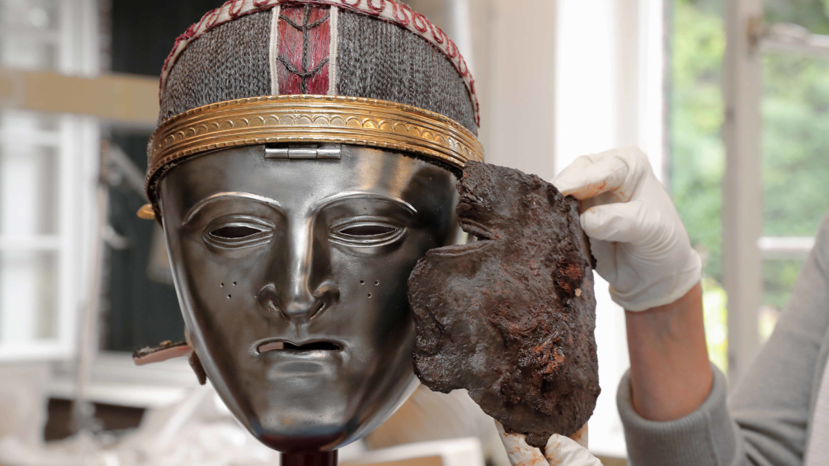 Das Maskenfragment wurde in Krefeld-Gellep bei einer Ausgrabung entdeckt; hier mit einer Nachbildung einer Gesichtsmaske der Bataver samt Helm.  Bild: Stadt Krefeld, Presse und Kommunikation